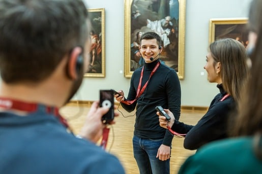 A tour guide using a Chierda wireless tour guide system to communicate with her group in a museum.